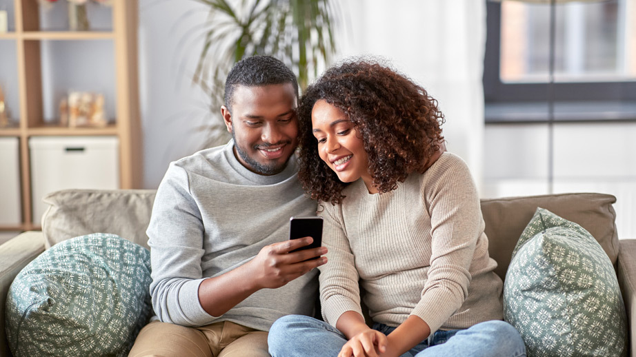 Man and woman sitting on couch looking at phone